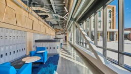 image of the wall of lockers and seating area for students to gather their belongings with floor-to-ceiling windows overlooking courtyard.