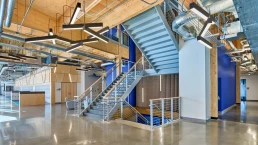 Photo of stair case and open floor plan of the 2nd floor with soft lounge seating and wall of lockers for the students