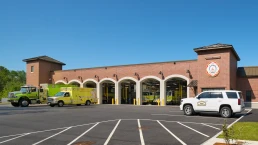Exterior view of the Brunswick Fire Station, showcasing its brick facade and large equipment bays with fire trucks visible.