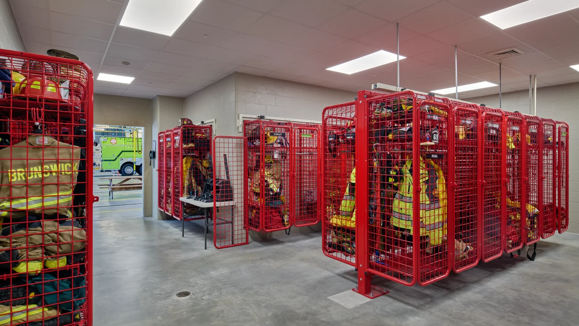 Firefighter gear organized in red storage cages inside the Brunswick Fire Station.